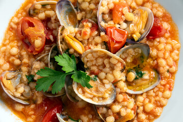 Primo piano di deliziosa fregula con vongole e pomodorini, piatto di pasta tradizionale sarda, cibo italiano 