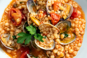 Primo piano di deliziosa fregula con vongole e pomodorini, piatto di pasta tradizionale sarda, cibo...