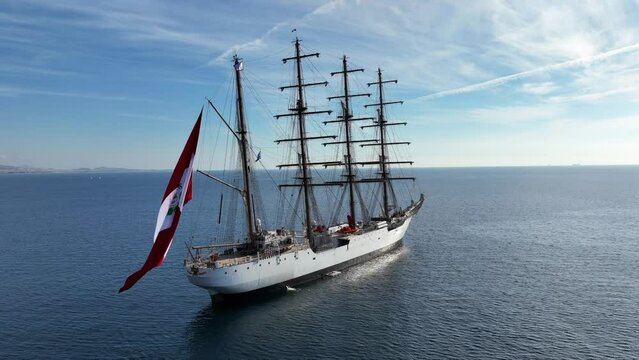 Aerial drone video of beautiful 3 mast barque or barc type classic sailing wooden boat anchored in Mediterranean deep blue sea