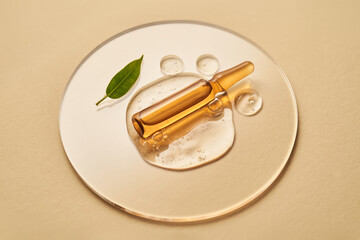 Ampoule in a drop of cosmetic gel on a beige background.