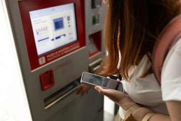 Young woman buying tickets for public transportation. A woman uses a self-service kiosk, Modern technology concept - obrazy, fototapety, plakaty