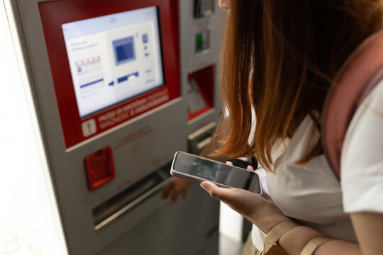 Young woman buying tickets for public transportation. A woman uses a self-service kiosk, Modern technology concept