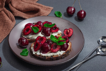 Fresh bread sandwiches with sweet cherry, cream cheese and mint leaves. Morning breakfast concept