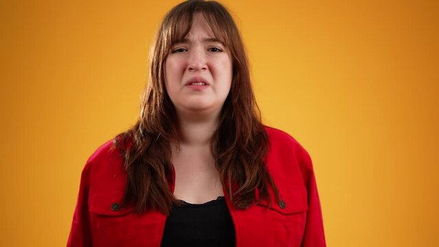 Pretty brunette young woman 20s did not get enough sleep last night after party and barely got up in the morning yawning. Portrait isolated on yellow background in studio in slow motion