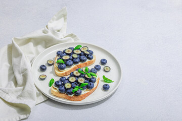 Fresh bread sandwiches with sweet blueberries, cream cheese and basil leaves. Good morning concept