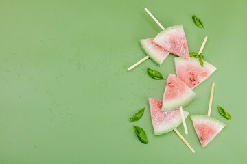 Frozen watermelon popsicles on trendy Savannah green background. Refreshing summer dessert