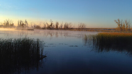 Colorful fog over the lake in autumn at dawn
