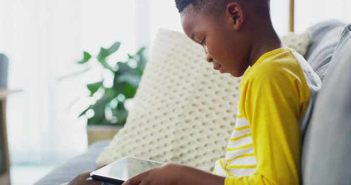 Child, boy and tablet, e learning or reading ebook with website for education gaming or video game. Young kid relax on couch, digital tech and connectivity, online course or gamer streaming at home