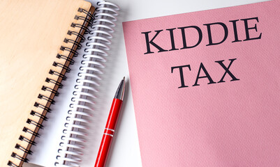 KIDDIE TAX word on the pink paper with office tools on white background