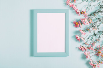 Beautiful flowers composition. Light pink flowers, empty photo frame for text on pastel blue background. Wedding. Birthday. Valentines Day. Mother's day. Flat lay, top view, copy space