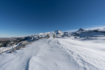 Fototapeta na wymiar two mountaineers on their backs walking in a snowy mountain landscape. France Pyrenees