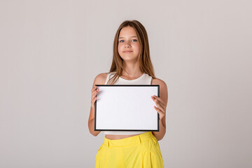 White banner .Teenager girl hold white blank paper. Young smiling woman show blank board. Close up female model portrait on white background.