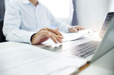 Close-up shot, business consultant reviewing documents and contact customer via laptop to give...