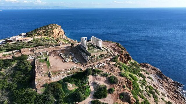 Aerial drone video of iconic archaeological site of Cape Sounio and famous Temple of Poseidon built uphill overlooking Aegean sea, Attica, Greece