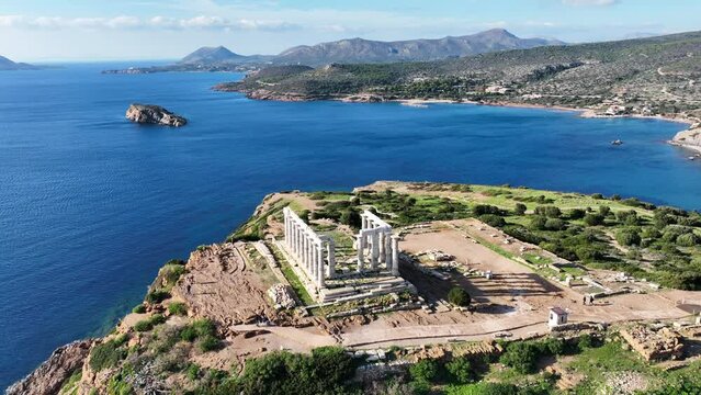 Aerial drone video of iconic archaeological site of Cape Sounio and famous Temple of Poseidon built uphill overlooking Aegean sea, Attica, Greece