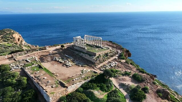 Aerial drone video of iconic archaeological site of Cape Sounio and famous Temple of Poseidon built uphill overlooking Aegean sea, Attica, Greece