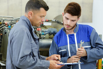 Obraz premium apprentice mechanic and mentor analyzing broken part