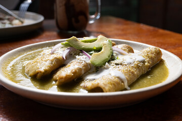 Plato de enchiladas verdes platillo tradicional mexicano con un fondo de madera