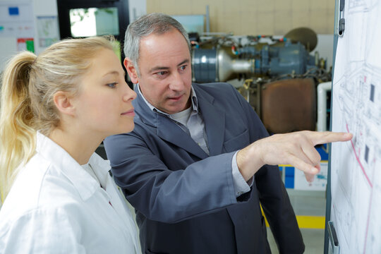 engineer showing intern a blueprint
