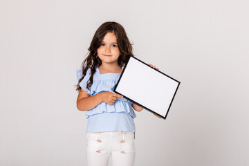 White banner. Little child girl model in summer blue and white cloth on white background hold white blank paper. Young smiling girl show blank board.