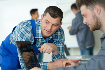 automotive mechanic apprentice studying using a laptop