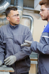 two male engineers in discussion in factory - obrazy, fototapety, plakaty