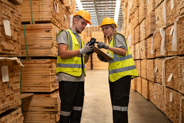 Caucasian businessman and woman checking timber stock with bar code scanner at wood stock warehouse	
