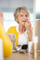 mature woman applying make-up at her dressing table