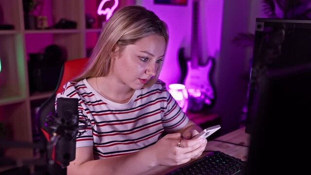 A focused young woman examines a card while sitting in a well-lit gaming room at night.