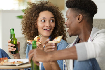 happy relaxed couple sharing pizza and beer at home