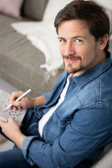 Obraz premium young man sitting doing a crossword puzzle