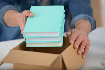 hands packing her books and stuff to move flat