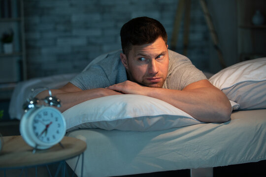man with sleeping problem at his bed at home