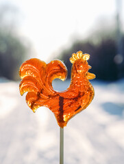 Cockerel candy. Russian lollipop against the backdrop of a winter landscape