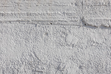 rough whitewash or white plaster wall under direct sunlight, full-frame background and texture.