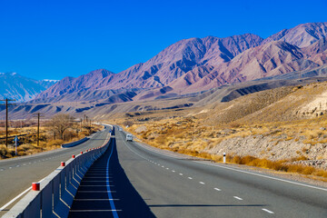 empty highway road with separating concrete barrier in mountains at sunny autumn day.