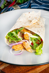 Wholegrain tortilla wraps with vegetables and chicken on a plate.