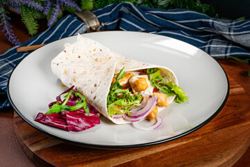 Wholegrain tortilla wraps with vegetables and chicken on a plate.