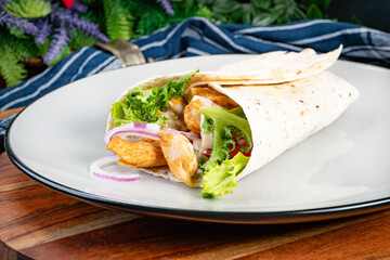 Wholegrain tortilla wraps with vegetables and chicken on a plate.