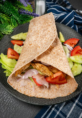 Wholegrain tortilla wraps with vegetables and chicken on a plate.