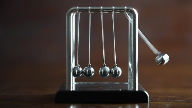 Metal Newton cradle placed on wooden background as representation of momentum concept, cradle balance steel balls, school teaching supplies, desk toy, gifts home decoration