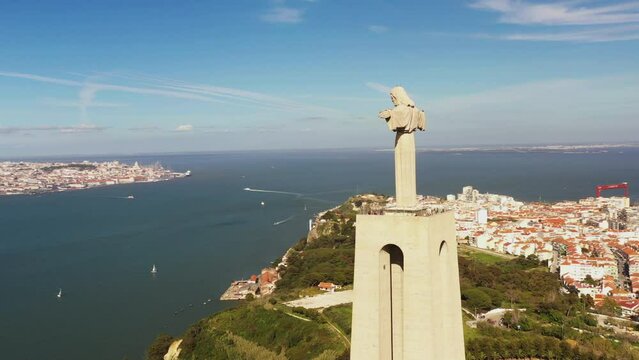 Captivating aerial panorama circles Cristo Rei statue, Tagus River, and Lisbon. A mesmerizing view of iconic landmarks and scenic beauty.