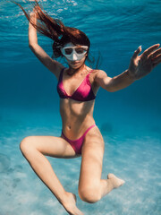 Fototapeta premium Young woman in bikini swimming underwater in blue ocean.