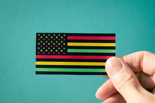 Juneteenth Freedom Day banner. African - American Independence day. A woman's hand holds an American flag on a turquoise, black history month concept.