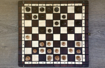 The chess board with the pieces in the dark vintage room interior