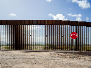 Stop sign at the United States border wall with Mexico, near Lukeville, Arizona.