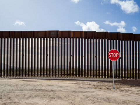 Stop sign at the United States border wall with Mexico, near Lukeville, Arizona.