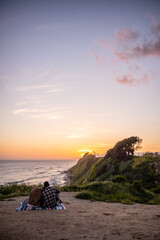 Young couple watching sunset on bluffs near Santa Barbara, California