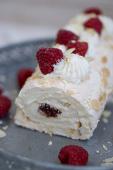 Homemade Mringue Pavlova roll cake with whipped cream and fresh raspberries on top close up selective focus