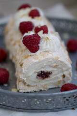 Homemade Mringue Pavlova roll cake with whipped cream and fresh raspberries on top close up selective focus